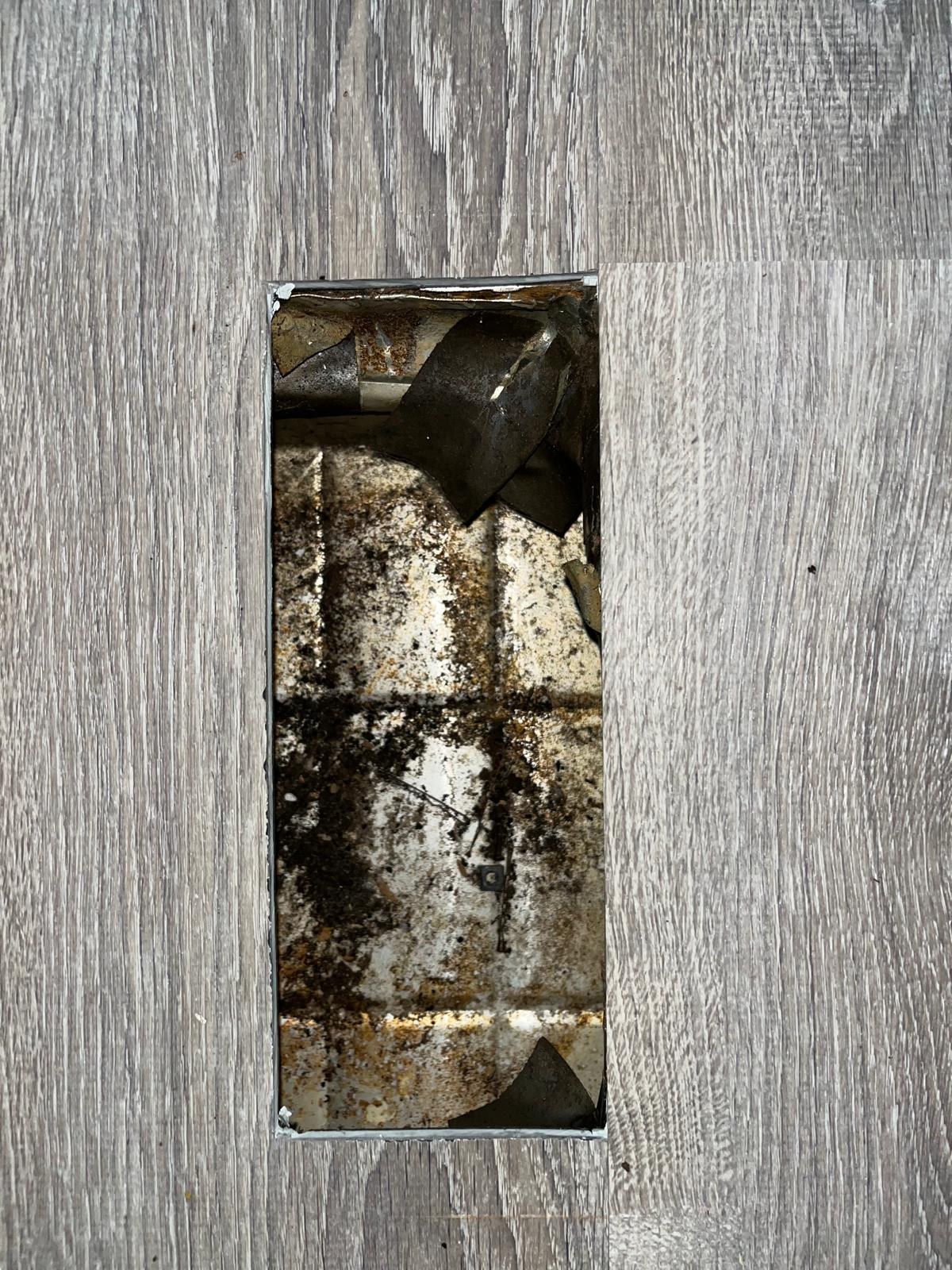 Dirty floor supply vent and duct boot before air duct cleaning in Vero Beach, FL