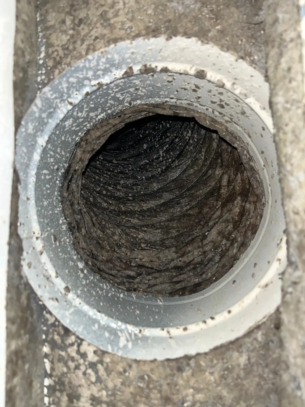 Dryer vent wall collar caked with compacted lint before cleaning at a Treasure Coast home
